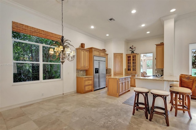 kitchen with a notable chandelier, tasteful backsplash, visible vents, light stone countertops, and built in refrigerator