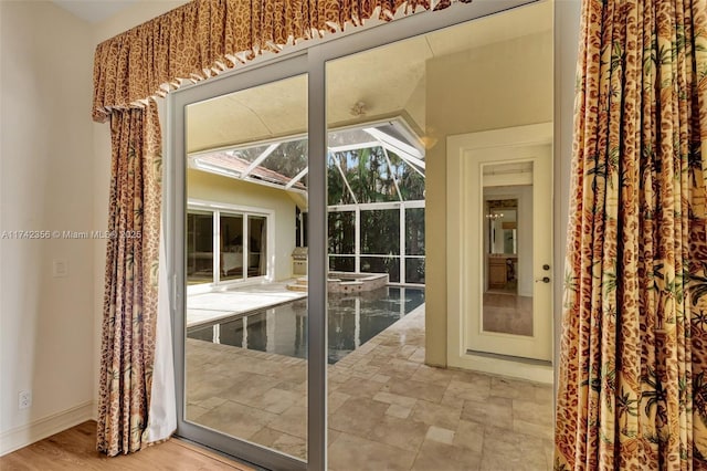 entryway with a sunroom, stone finish flooring, and baseboards