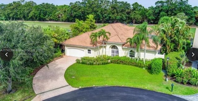 mediterranean / spanish house with a garage, concrete driveway, a front lawn, and a tiled roof