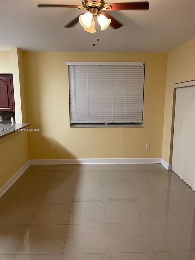 tiled empty room featuring ceiling fan