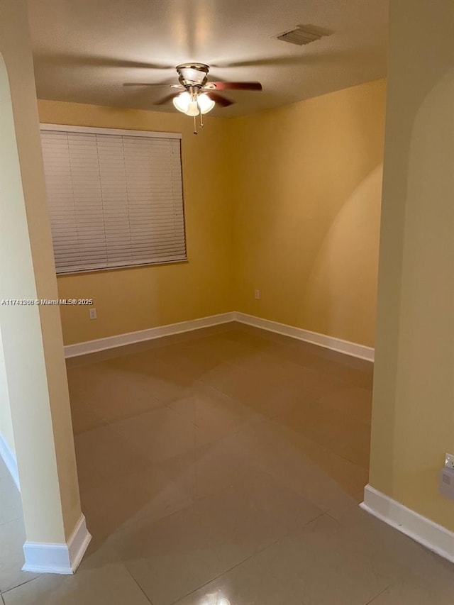 tiled spare room featuring ceiling fan