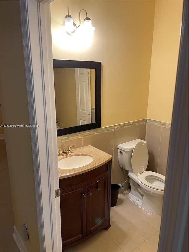 bathroom featuring tile patterned flooring, vanity, tile walls, and toilet