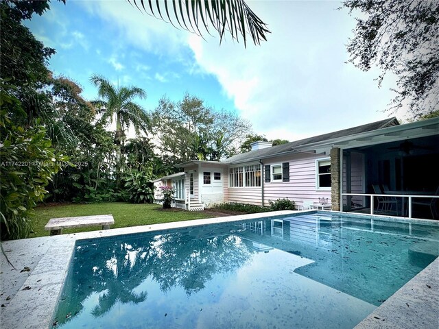 view of pool with a yard and a sunroom