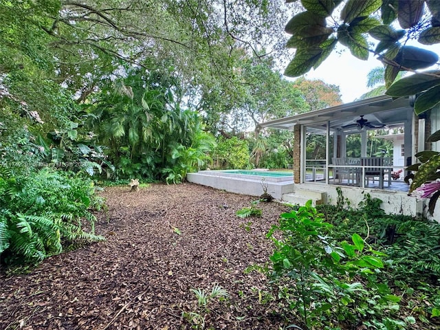 view of yard featuring a sunroom, an outdoor pool, and ceiling fan