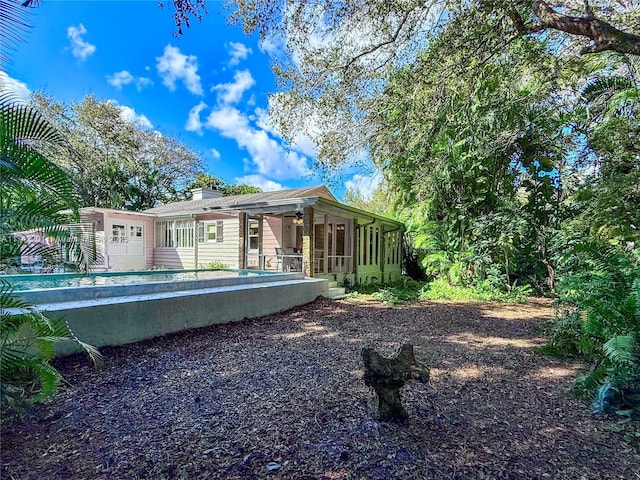 back of house featuring a sunroom and ceiling fan