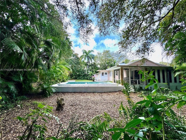view of yard featuring a sunroom and an outdoor pool