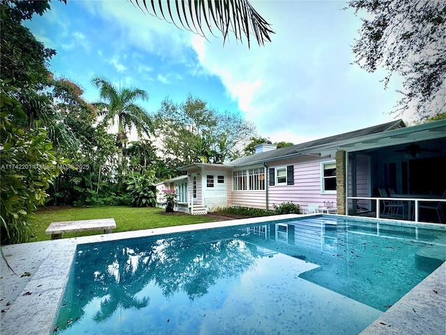 outdoor pool with a patio area, a lawn, and ceiling fan