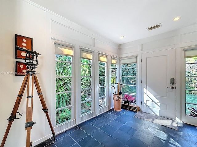entryway featuring crown molding, a decorative wall, visible vents, and recessed lighting