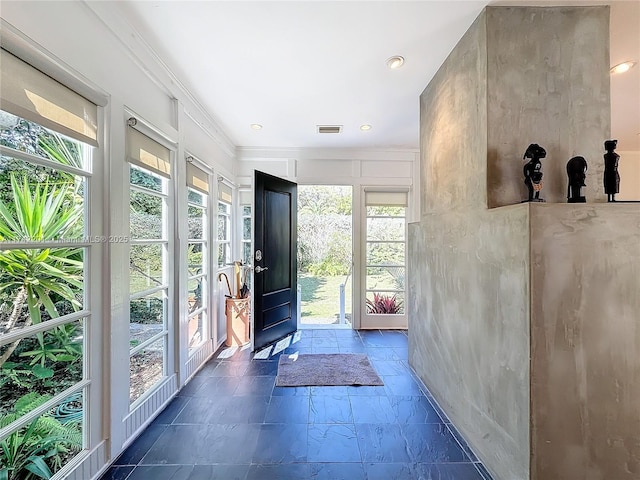 doorway to outside featuring visible vents, a wealth of natural light, and stone tile flooring