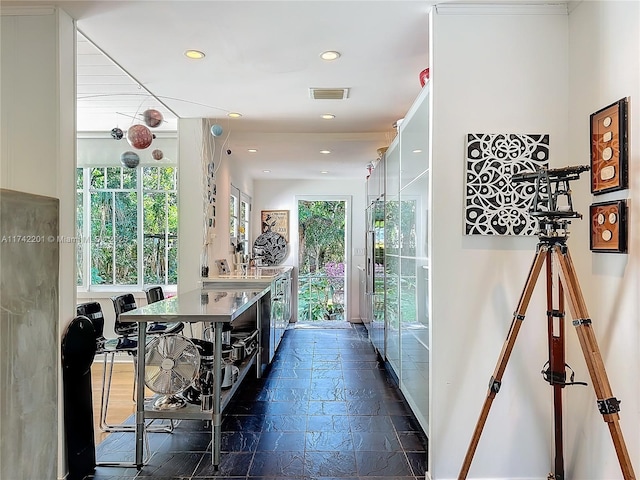 hall featuring stone tile flooring, baseboards, visible vents, and recessed lighting