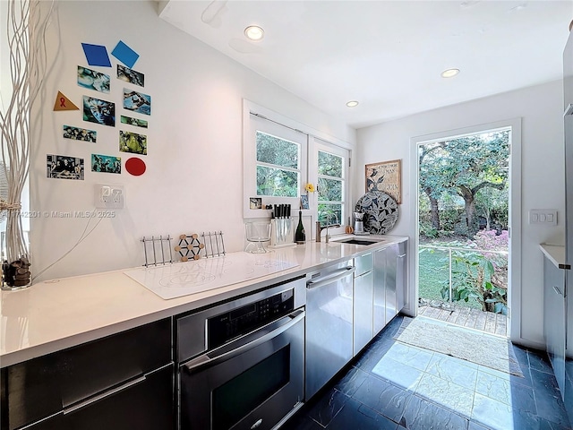 kitchen with light countertops, appliances with stainless steel finishes, a sink, and recessed lighting