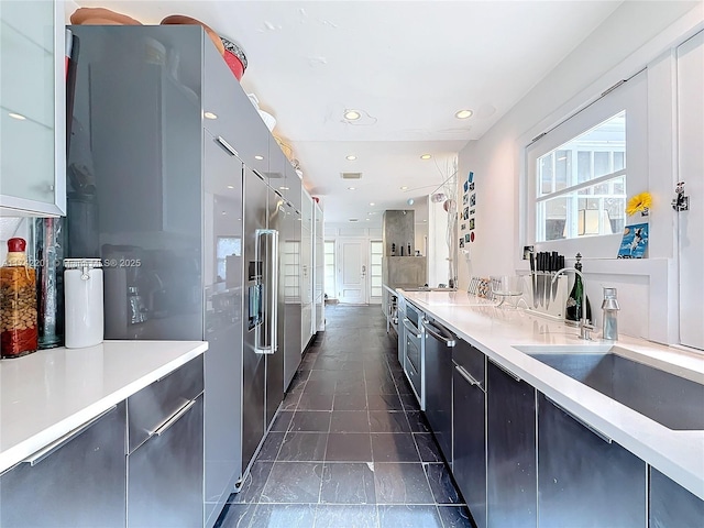 kitchen with a sink, light countertops, recessed lighting, and modern cabinets