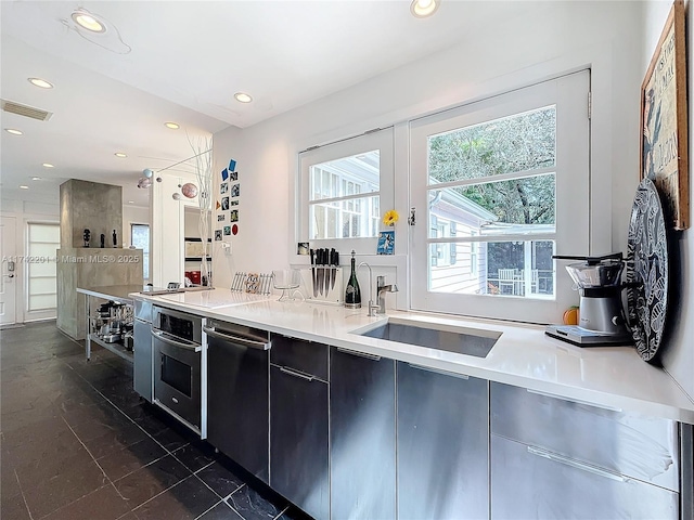 kitchen featuring modern cabinets, a sink, light countertops, recessed lighting, and stainless steel appliances