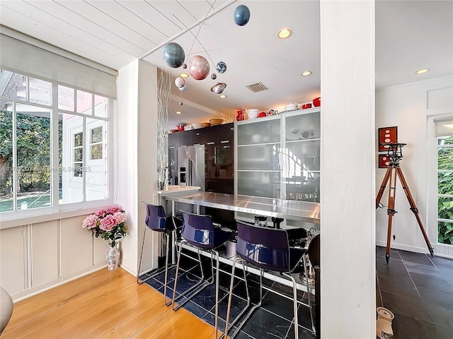 bar with ornamental molding, recessed lighting, visible vents, high end refrigerator, and wood finished floors