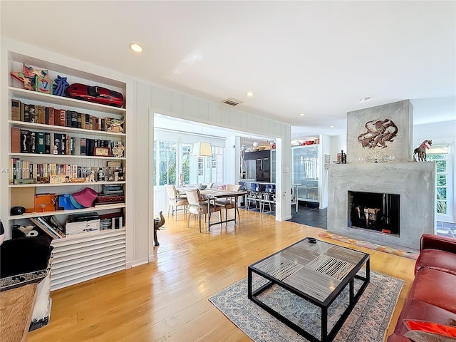 living area featuring wood finished floors, a fireplace, visible vents, and recessed lighting