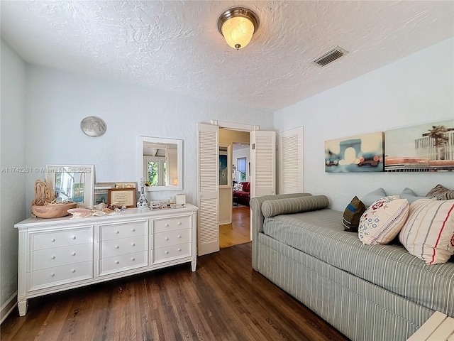 bedroom featuring visible vents, a textured ceiling, and dark wood-style floors