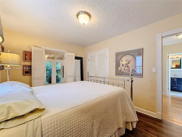 bedroom with a sink, baseboards, wood finished floors, and a textured ceiling