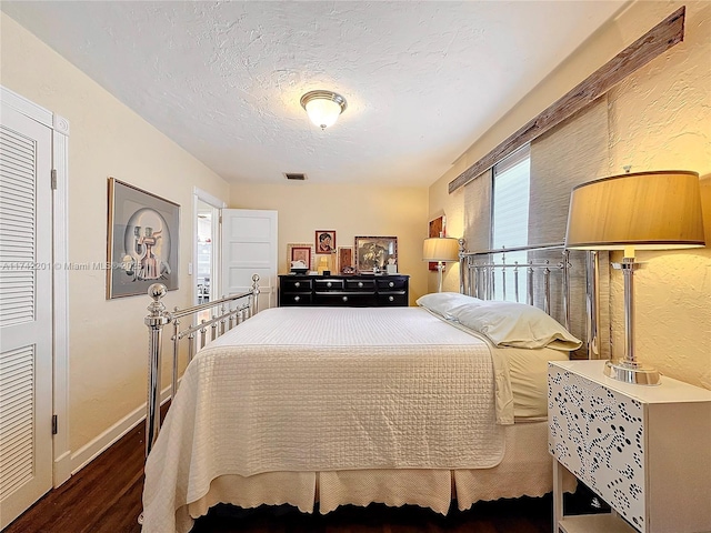 bedroom with a textured ceiling, wood finished floors, and visible vents