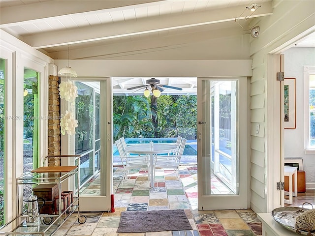 doorway to outside featuring stone finish flooring, vaulted ceiling with beams, and a ceiling fan