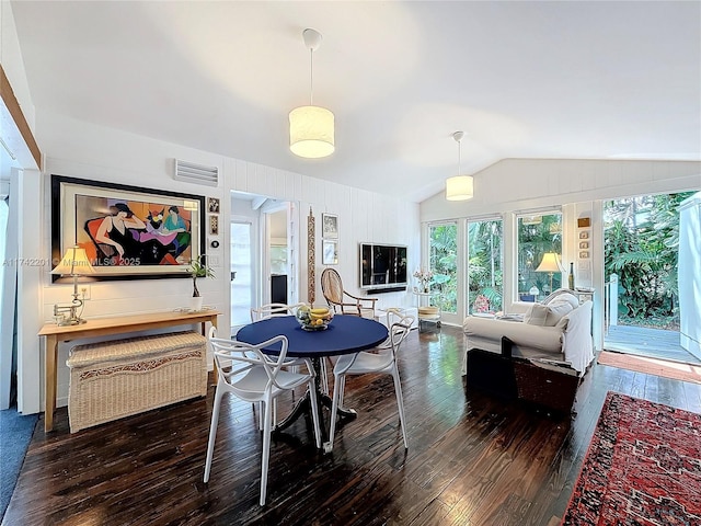 dining area featuring hardwood / wood-style floors, lofted ceiling, and visible vents