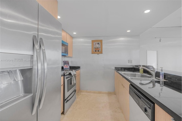 kitchen with dark stone countertops, sink, stainless steel appliances, and light brown cabinets