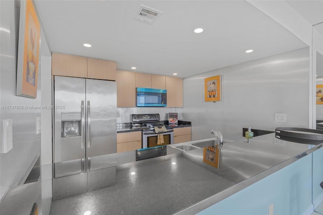 kitchen with stainless steel appliances, sink, light brown cabinetry, and kitchen peninsula