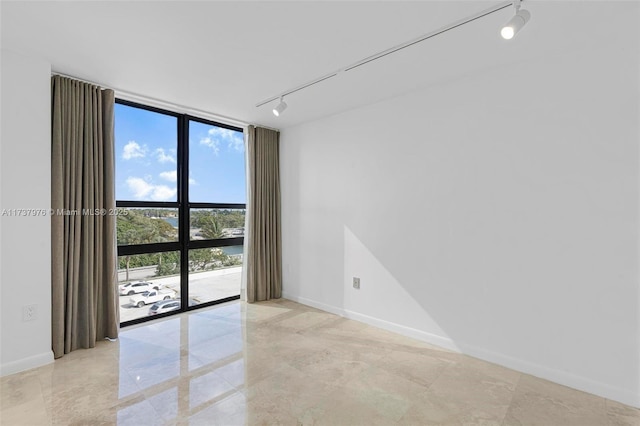 empty room featuring track lighting and floor to ceiling windows