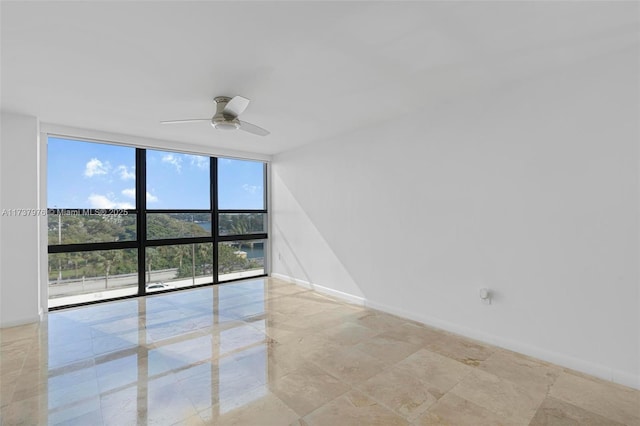 empty room featuring expansive windows and ceiling fan