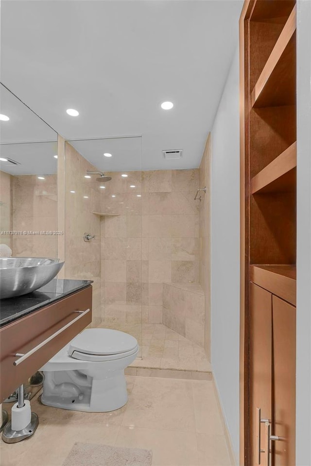 bathroom with a tile shower, vanity, and toilet