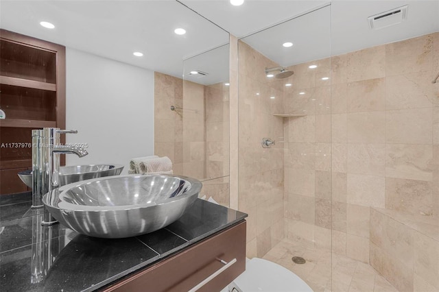 bathroom featuring vanity, toilet, and a tile shower