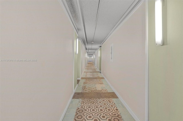 corridor featuring ornamental molding, a textured ceiling, and light tile patterned floors