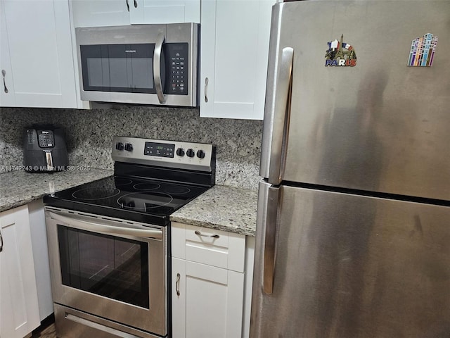 kitchen featuring white cabinetry, tasteful backsplash, light stone countertops, and appliances with stainless steel finishes