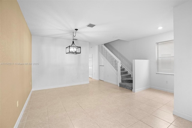 tiled empty room with a notable chandelier