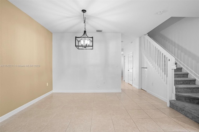 spare room featuring light tile patterned floors and a chandelier