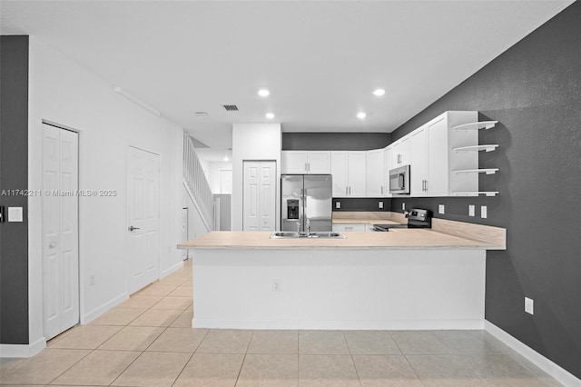 kitchen with appliances with stainless steel finishes, sink, white cabinets, light tile patterned floors, and kitchen peninsula