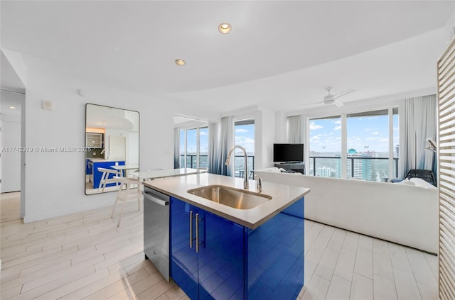 kitchen with sink, blue cabinetry, ceiling fan, dishwasher, and a center island with sink