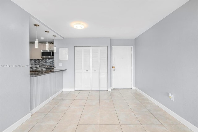 kitchen featuring hanging light fixtures, tasteful backsplash, range, and light tile patterned floors