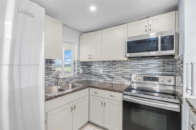 kitchen featuring dark stone countertops, sink, white cabinets, and appliances with stainless steel finishes