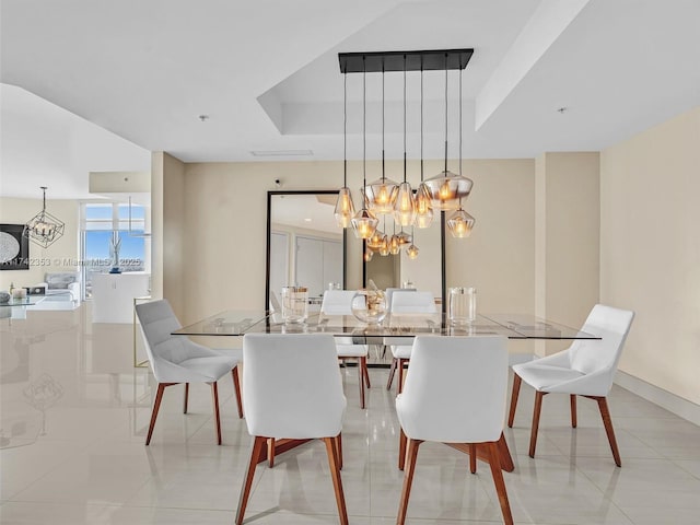 dining space featuring a tray ceiling, light tile patterned floors, and a notable chandelier