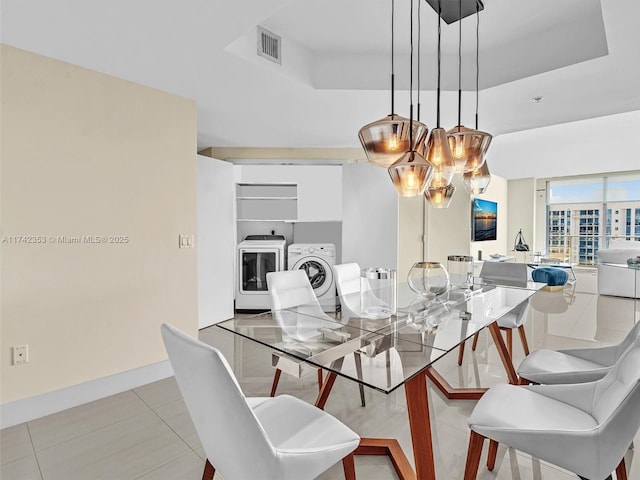 tiled dining area with a tray ceiling and washer and dryer