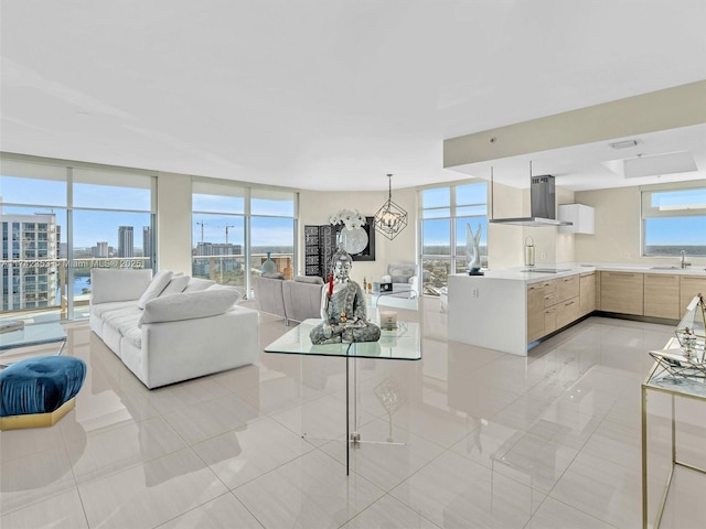 tiled living room featuring sink, a wall of windows, a chandelier, and plenty of natural light