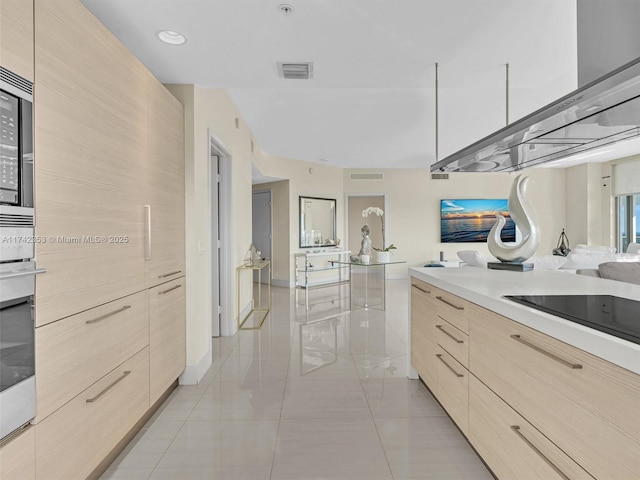 kitchen featuring light brown cabinetry, oven, light tile patterned floors, black electric stovetop, and wall chimney exhaust hood