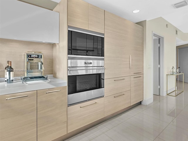 kitchen with built in microwave, light tile patterned floors, and light brown cabinetry