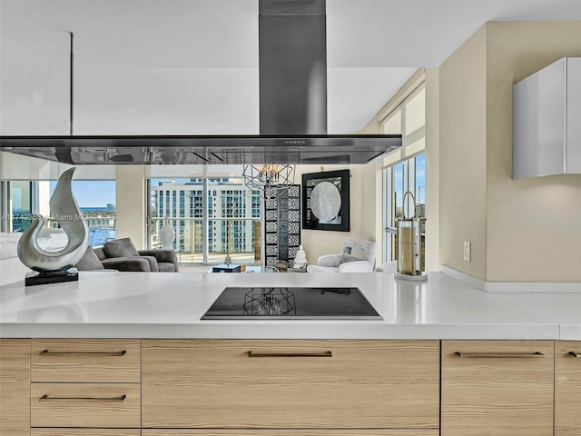 kitchen with light stone counters, black electric stovetop, a healthy amount of sunlight, and light brown cabinets