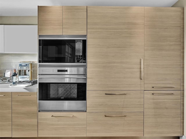 kitchen featuring built in microwave, stainless steel oven, and light brown cabinets