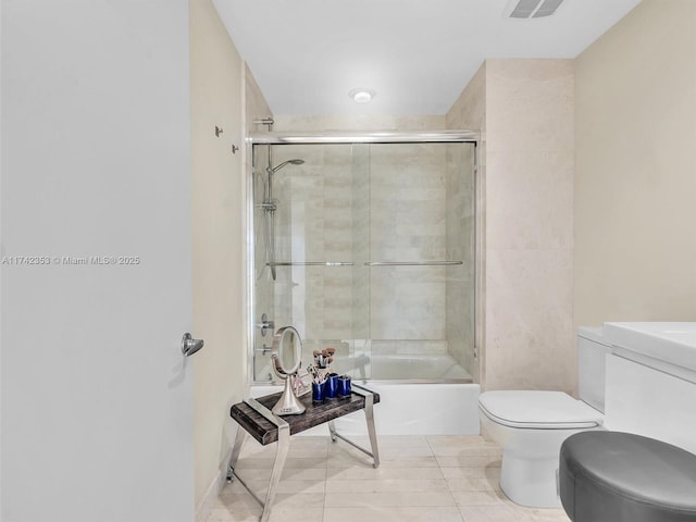 bathroom with tile patterned flooring, bath / shower combo with glass door, and toilet