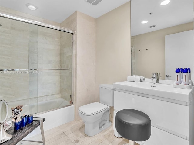 full bathroom with bath / shower combo with glass door, vanity, tile patterned floors, and toilet