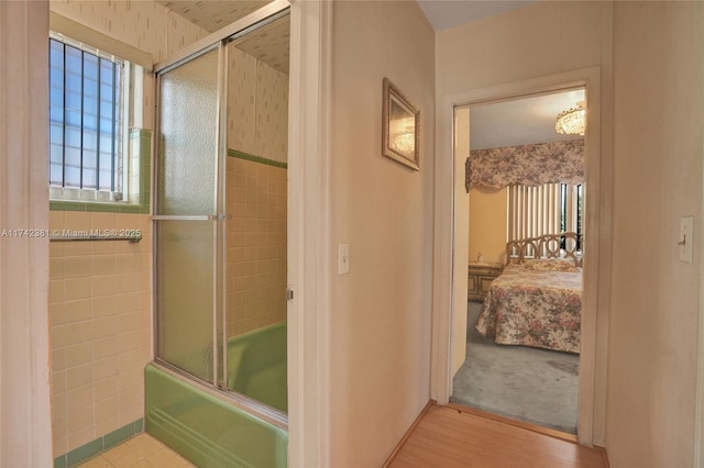 bathroom with wood-type flooring and combined bath / shower with glass door