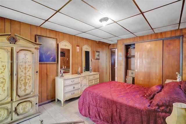 bedroom featuring a paneled ceiling, a closet, and wood walls