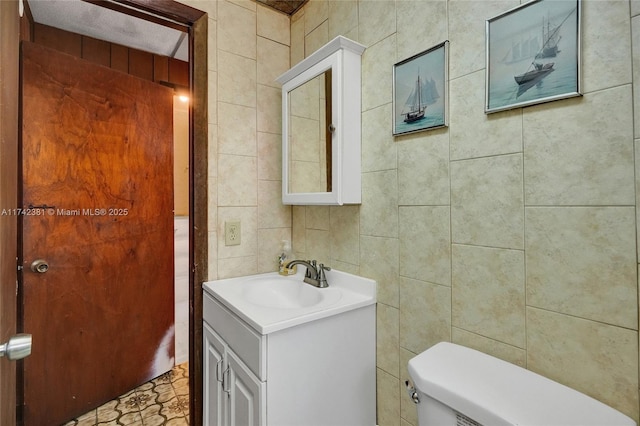 bathroom featuring vanity, toilet, and tile walls